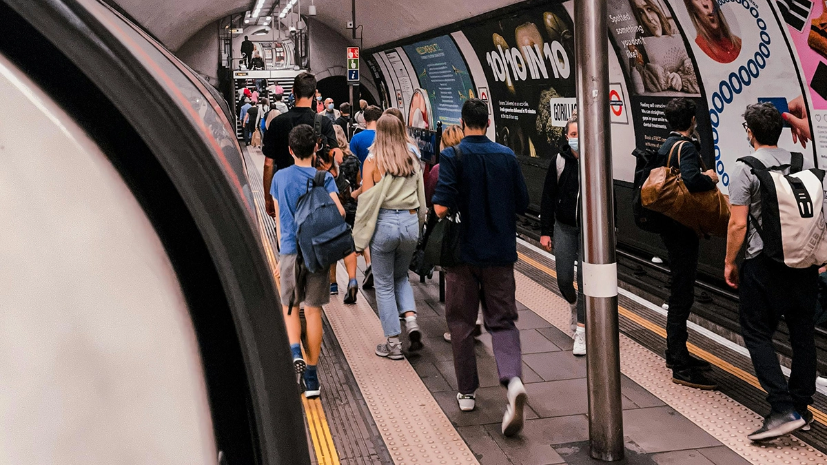 Cross track platform level posters at Camden Town with a crowd of commuters