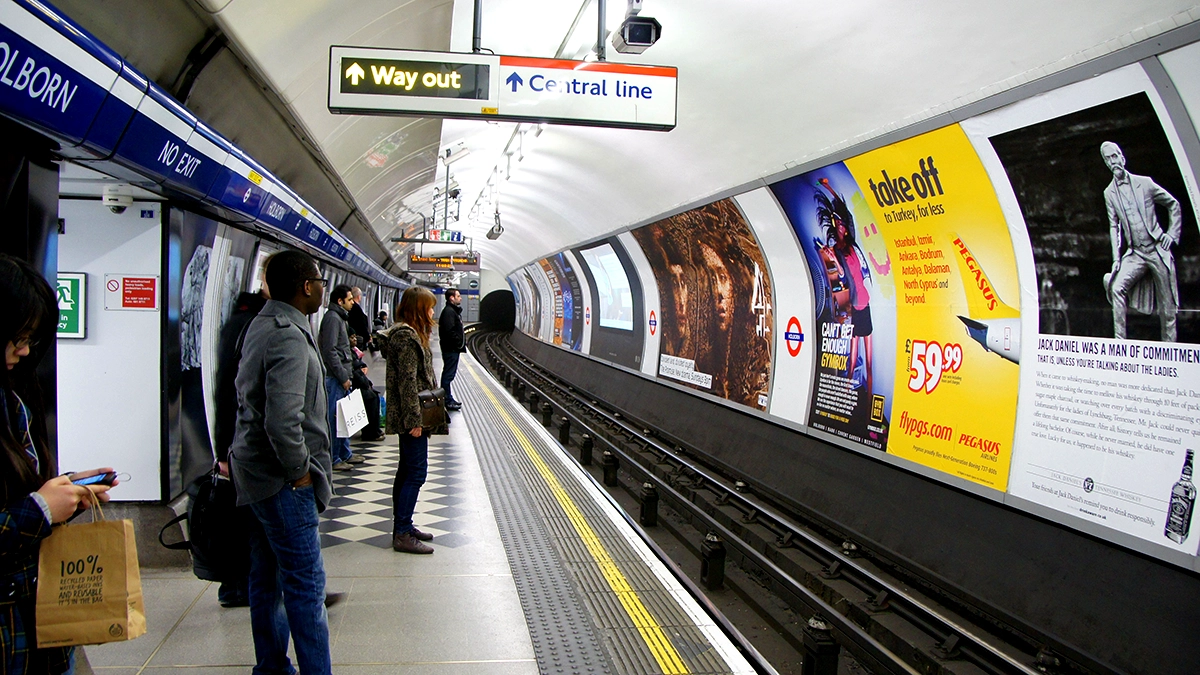 Commuters looking at the cross track adverts on the platform level at Holborn tube station