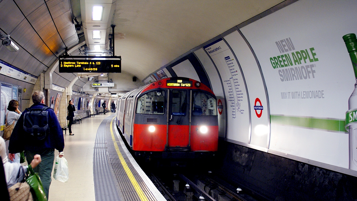 Commuters looking at cross track adverts at Knightsbridge station as a tube arrives into the platform