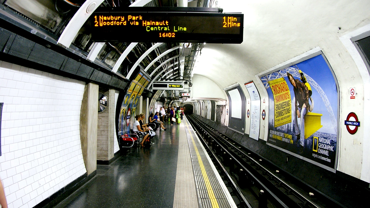 Waiting commuters look at 48 sheet cross track adverts at Marble Arch station