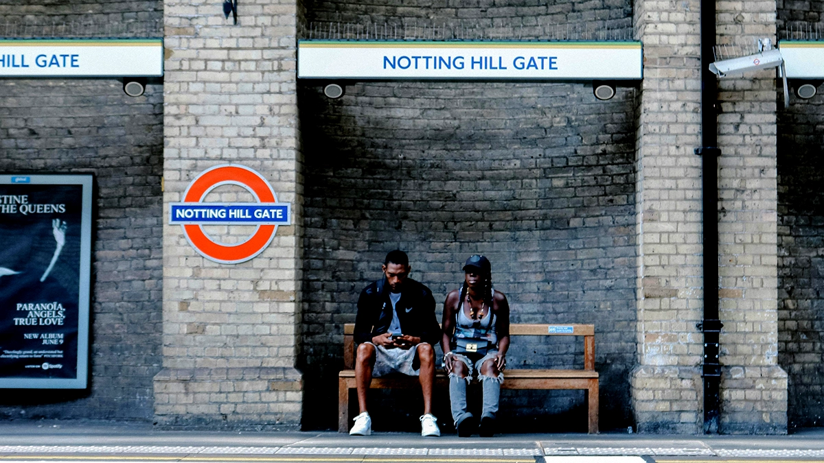 Two commuters wait for a train at Notting Hill Gate station
