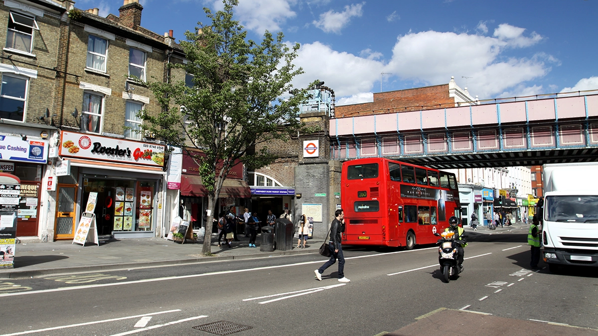 Shepherd's Bush Market station entrance taken from Uxbridge Road with local shops and the railway bridge