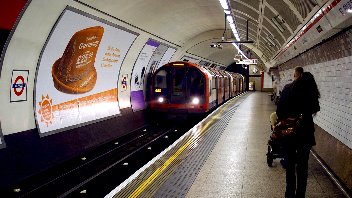 Tube train entering St. Paul's tube station in from of a 48 sheet cross track advert