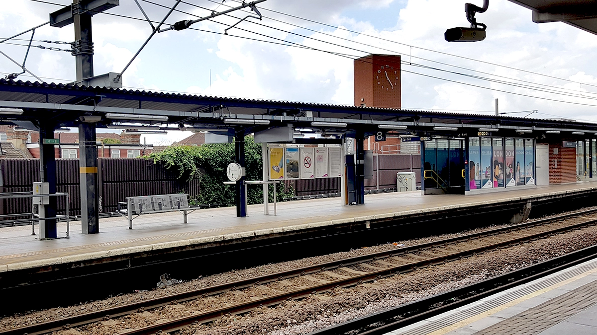 A view across the train tracks at West Ham underground station with a clock tower in the background
